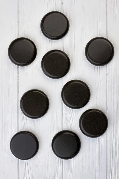 Černé leštěné kulaté kameny na bílém dřevěném stole. — Stock fotografie