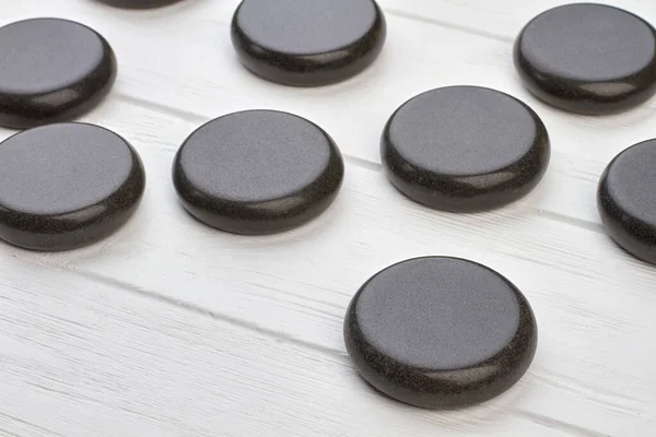 Close-up zwart gepolijste ronde stenen op wit houten bureau. — Stockfoto