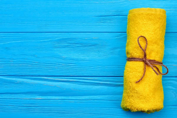 Asciugamano di spugna da bagno giallo laminato su scrivania di legno blu. — Foto Stock