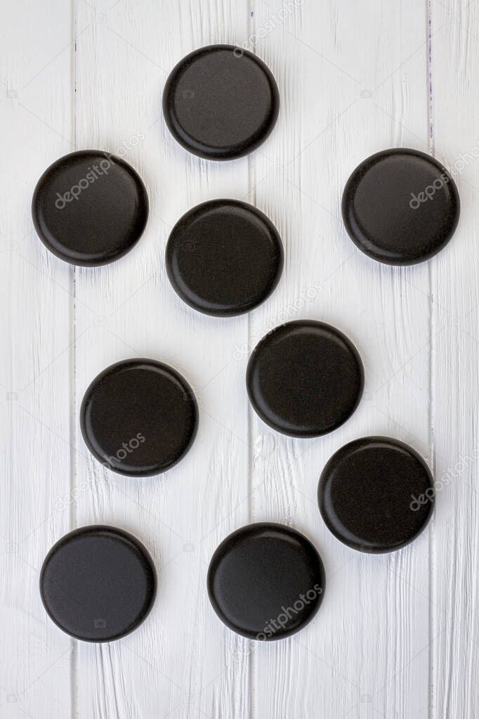 Black polished round stones on white wooden desk.