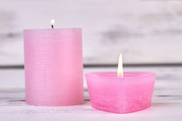 Brennende rosa Wachskerzen auf weißem Holzgrund. — Stockfoto