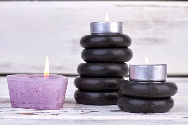 Brennende Kerzen mit schwarzen Steinen auf weißem Hintergrund. — Stockfoto