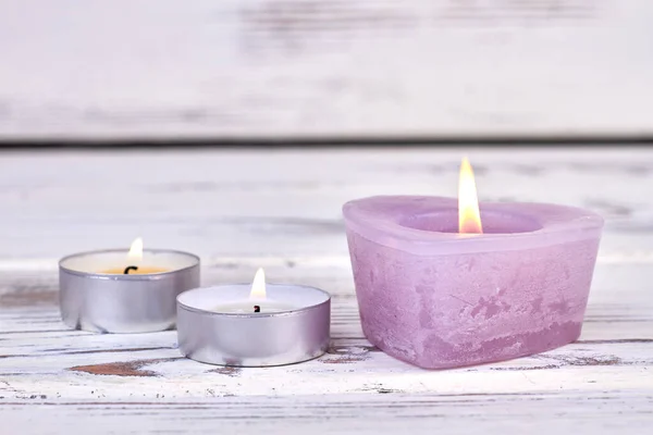 Velas de cera ardiente de primer plano sobre fondo de madera blanco. —  Fotos de Stock