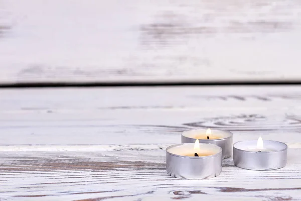 Três pequenas velas acesas na mesa de madeira branca. — Fotografia de Stock