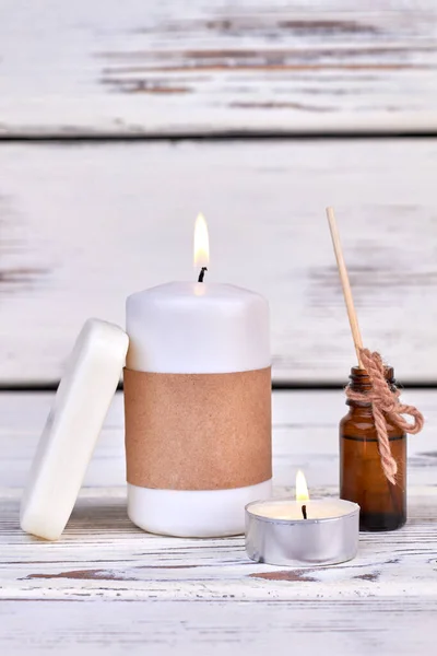 Brennende Aroma-Wellness-Kerzen mit glühenden Lichtern und einer Flasche Öl. — Stockfoto