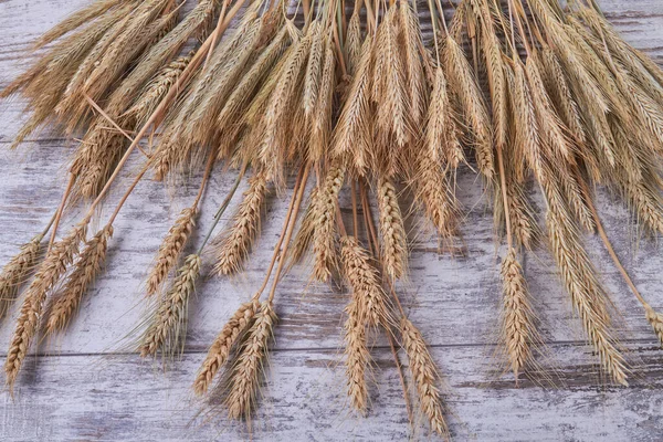 Högen med vete och råg spikelets på vit trä bakgrund. — Stockfoto