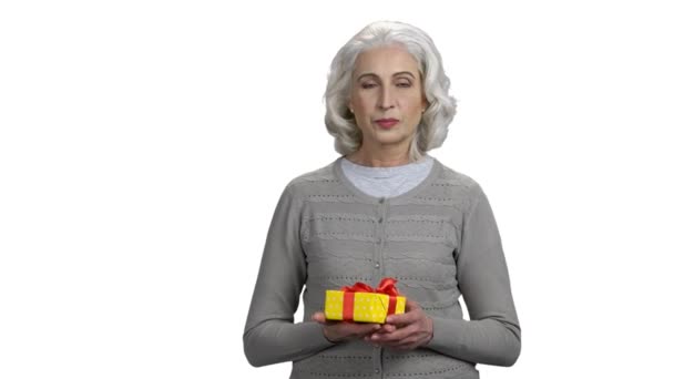 Ώριμη γυναίκα που παρουσιάζει κουτί δώρου σε λευκό φόντο. — Αρχείο Βίντεο