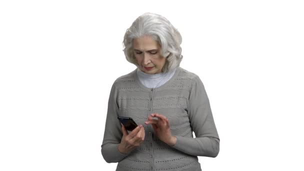 Glimlachende senior vrouw met behulp van smartphone op witte achtergrond. — Stockvideo