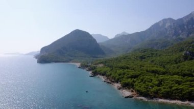 Deniz kıyısı ve kıyı şeridi manzaralı bir deniz manzarası. Dağlar ve kıyıdaki yeşil tropikal ormanlar.