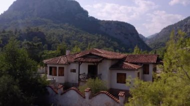 Dağlık ormanda modern bir ev. Arka planda bulutlu bir gökyüzü.