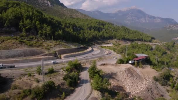 Вид с воздуха на дорогу с вождением автомобилей через лесистые горы. — стоковое видео