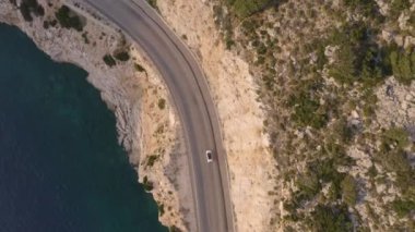 Mavi deniz kıyısında giden arabalı dağ yolunun manzaralı manzarası.