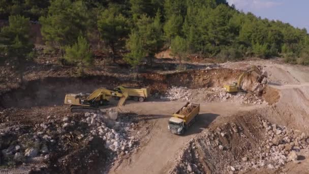 Vista aérea de la cantera de montaña. Las excavadoras cargan una piedra en los basureros. — Vídeos de Stock