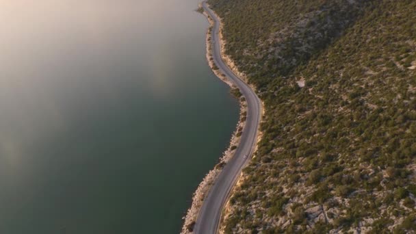 海と山の間の車と狭い道路上の空中ドローンビュー. — ストック動画