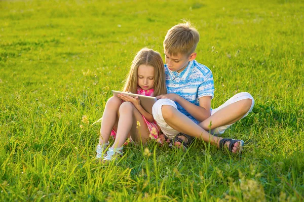 Garçon avec fille assis sur la pelouse . — Photo
