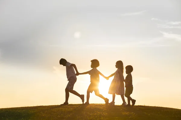 Vier kinderen spelen op zonsondergang. — Stockfoto