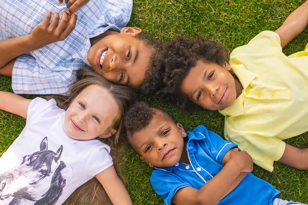 Four children are laying on the glade. — Stock fotografie