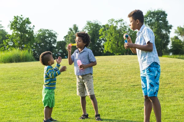 Three kids on glade with soap bubble.