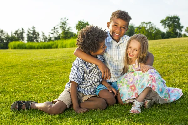 Three children are playing on the glade. — ストック写真