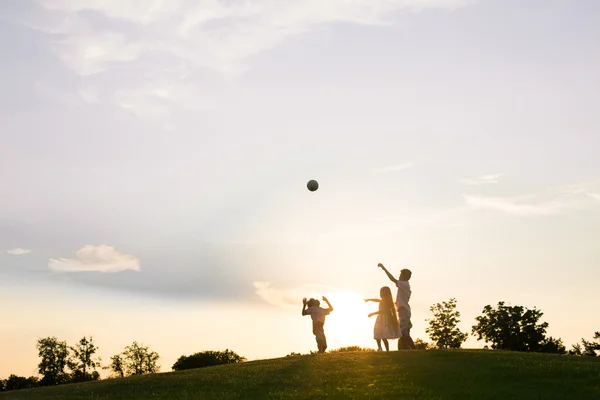 Three kids are playing on sunset. — Stock fotografie