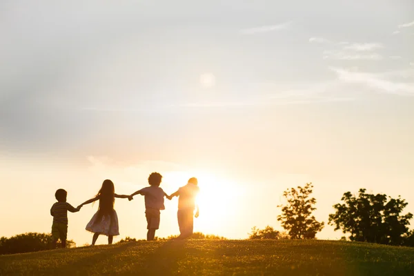 Cuatro niños juegan al atardecer. . — Foto de Stock