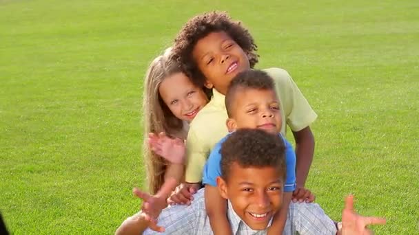 Vier kinderen spelen op het gras. — Stockvideo