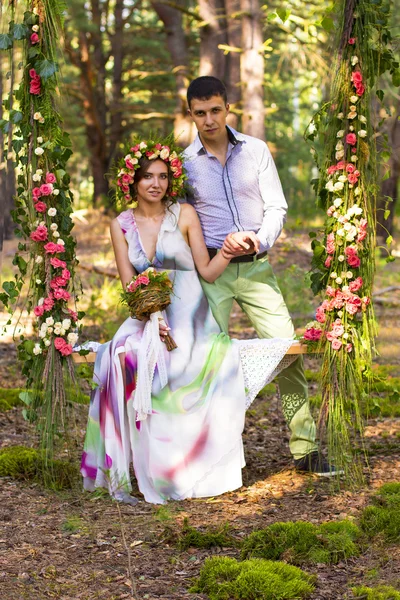 Beautiful couple on flower swing. — Stock Photo, Image