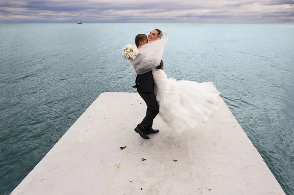 The groom is whirling his bride by the sea line. — Stock Photo, Image