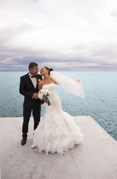 El novio y la novia se divierten junto al mar . — Foto de Stock