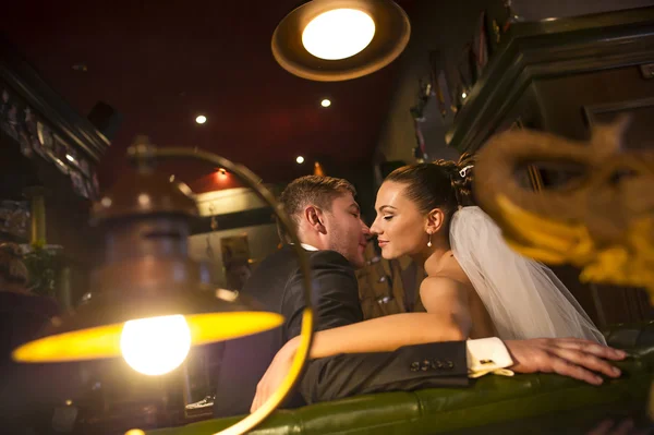 Newlyweds  on green sofa in the cafe. — Stock Photo, Image