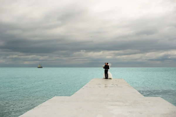 Pasgetrouwden zijn kussen op de achtergrond van de zee. — Stockfoto