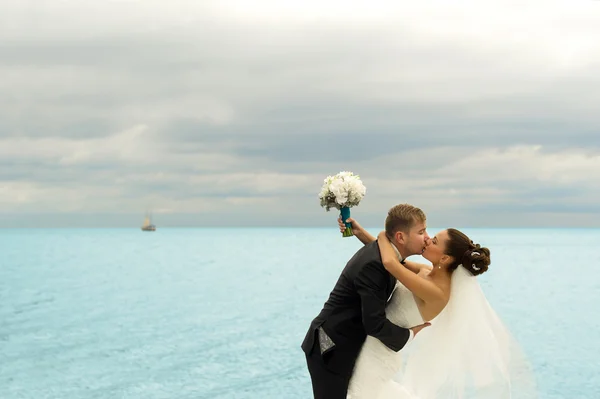 The groom is kissing her bride on the sea background. — Stock Photo, Image