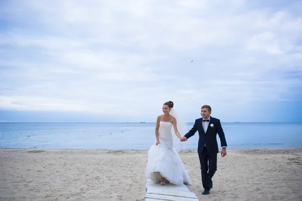 Los recién casados están caminando por la playa . — Foto de Stock