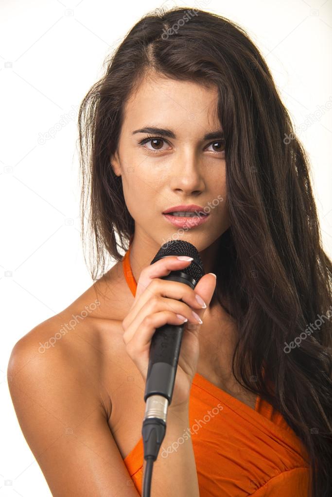 Impassioned girl in orange shirt with microphone.