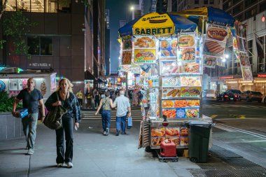 New York City, New York, ABD - 07.31.2024: Canlı Sabrett sokak yemekleri Times Meydanı 'nda parlak ışıklar altında kuzu pirinci, sosis ve mısırlı sosis sunmaktadır. Yayalar New York 'un enerji ve lezzet dolu kaldırımlarından geçiyorlar..