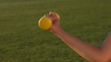 Kız onu pazı dumbbells ile sallar.