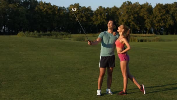 Парень и девушка делают селфи на поле для гольфа . — стоковое видео