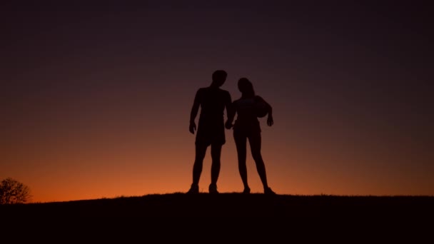Älskande par sportsmen promenad på kvällen kullarna. — Stockvideo
