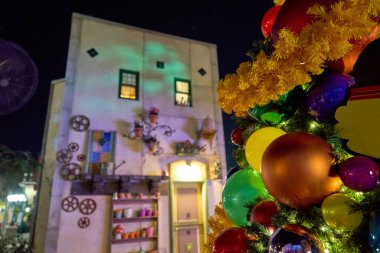 Neşeli bir tatil ağacı renkli mücevherlerle ve gülümseyen çizgi film yüzüyle kaplıdır. Parıldayan ışıklar gece parlıyor.