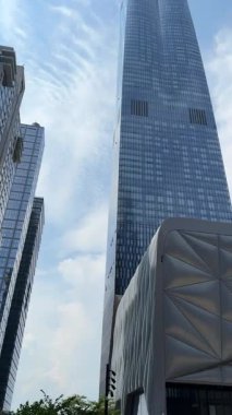 Uzun modern cam gökdelenler kültür merkezinin örtülü cephesinin üzerinde yükseliyor. Mavi gökyüzü, yansımalar ve keskin çizgiler Hudson Metrelerindeki modern New York mimarisini gösteriyor..