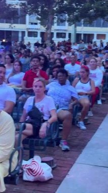 Orlando, Florida - 07.04.2024: Büyük bir çeşitlilik kentteki bir açık hava etkinliğini izlemek için banklarda oturuyor. İnsanlar bir halk toplantısında yaz akşamında birlikte rahatlar..