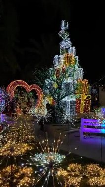 Yığınla parlayan bir heykel kalp kemeri ve parktaki yıldız patlaması ışıklarının yanında yükselir. Renkli tatil kurulumu akşam ziyaretçileri için parlak bir eğlence yarattı..