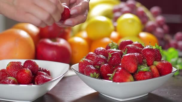 Vrouw reinigt een aardbei. — Stockvideo