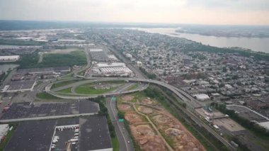 Nehir kıyısındaki bir şehre giden karmaşık bir otoyol kavşağının havadan görünüşü. Yerleşim bölgeleri ve sanayi bölgeleri kıyıya doğru uzanıyor..