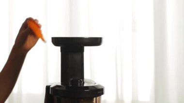 Kadının el ekleyerek havucu katı meyve sıkacağı.