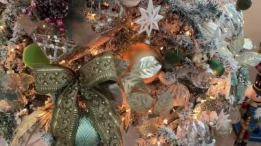 Bir noel ağacını desenli kurdele yayı, yıldız süslemeleri, kozalaklar ve cam takılarla kapatın. Sıcak ışıklar, bir ev içinde altın ve yeşil tatil süslemelerini ön plana çıkarıyor.