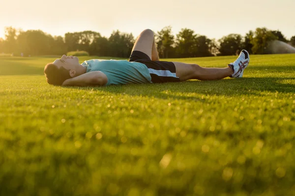 Guy lying in the park at sunset. — Stock Photo, Image