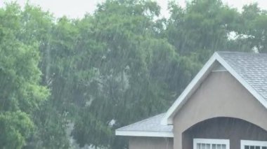 Şiddetli yağış, ağaçlar ve manzaralı bir evin üzerine yağar. Şiddetli fırtına banliyölerde dramatik bir hava durumu yaratıyor..
