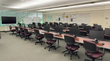 Orlando, Florida, ABD - 03.13.2024: Birden fazla masaüstü bilgisayarı sıralanmış modern bilgisayar sınıfı. Boş başkanlar ve monitörler sessiz bir akademik öğrenme ortamı yaratıyor.