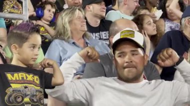 Orlando, Florida, ABD - 03.02.2024: Bir baba ve genç çocuk canlı bir etkinlik sırasında stadyum kalabalığında birlikte tezahürat yapıyorlar. Aileler gösterinin heyecanını yaşarken atmosfer enerjiktir..